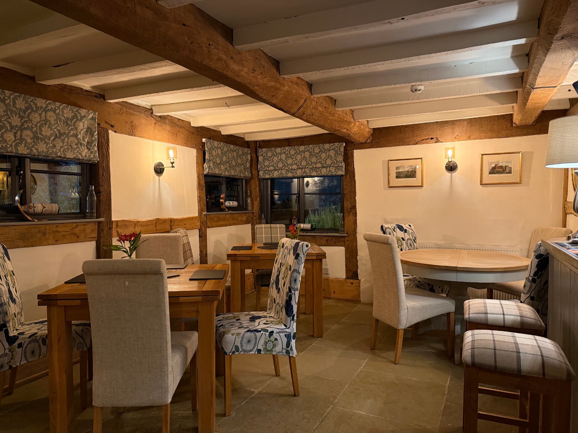 The beamed dining room at The Bell Inn, softly lit with candle-style wall lights